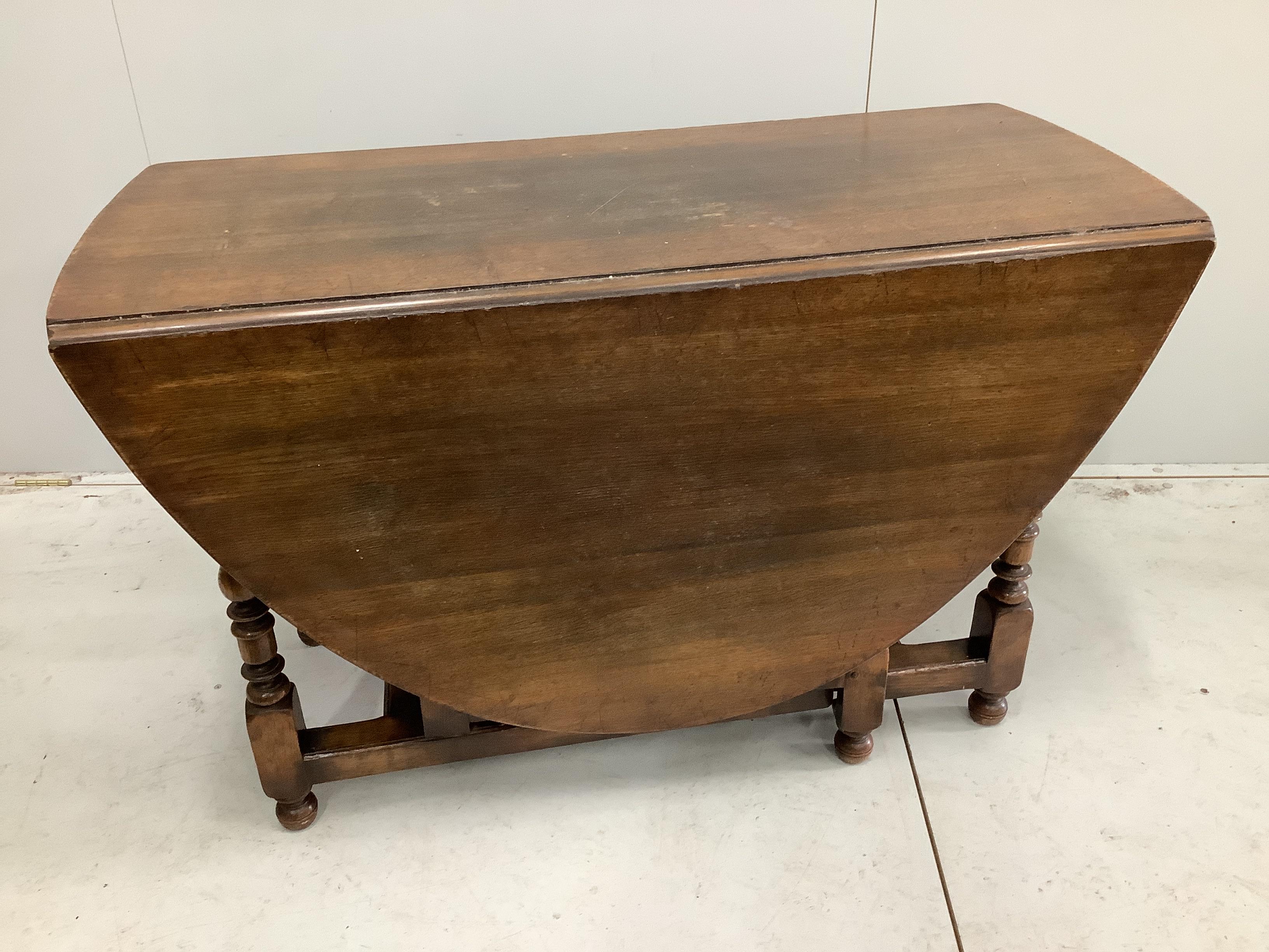 An 18th century style oak gateleg dining table, 170cm extended, depth 122cm, height 75cm together with a set of six oak ladderback dining chairs (one with arms)